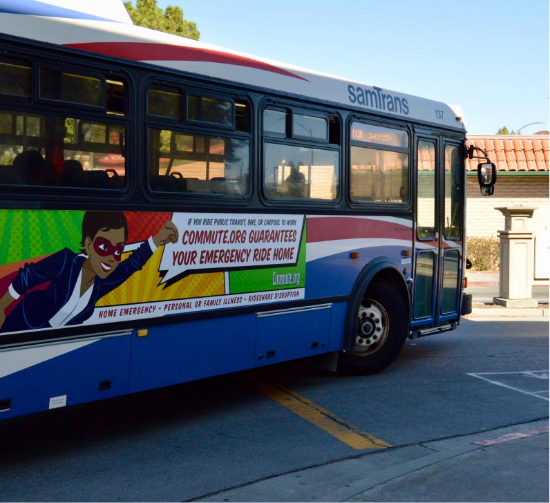 A SamTrans bus parked at a stop showcases an ad for Commute.org's guaranteed emergency ride home service.