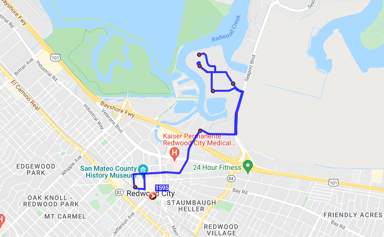 Map showing a blue path from downtown Redwood City, near Caltrain and landmarks like the San Mateo County History Museum, leading up to Seaport Centre by Redwood Creek, with several marked stops along the route.