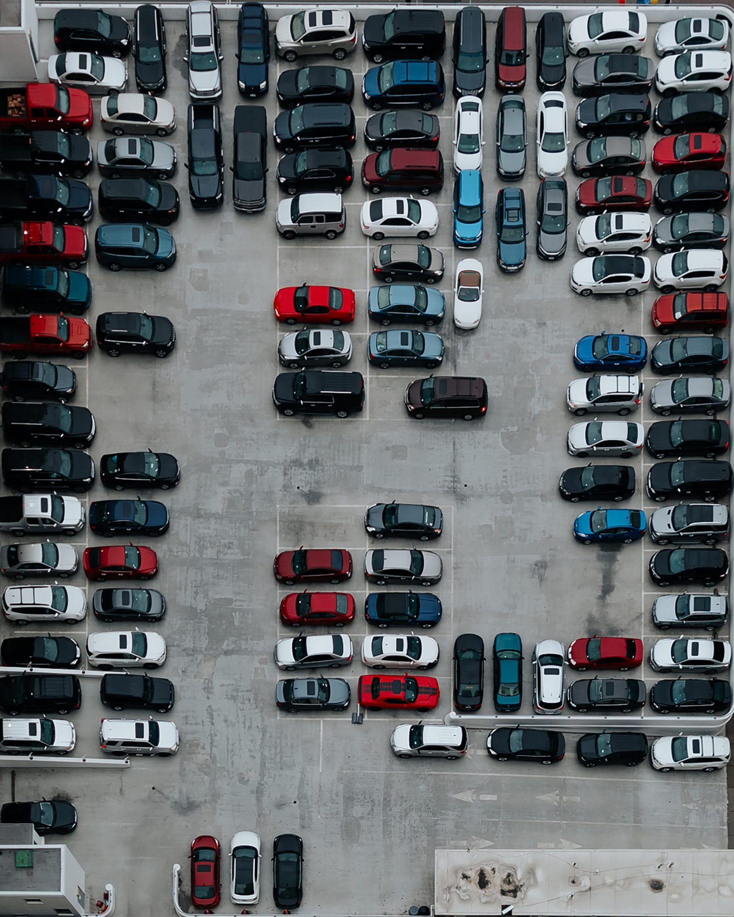 Aerial view of a densely packed parking lot, showcasing cars meticulously arranged to form the numbers "13" and "50." Black, white, red, and blue vehicles align on the concrete surface, reflecting orderly policies in vehicle placement.